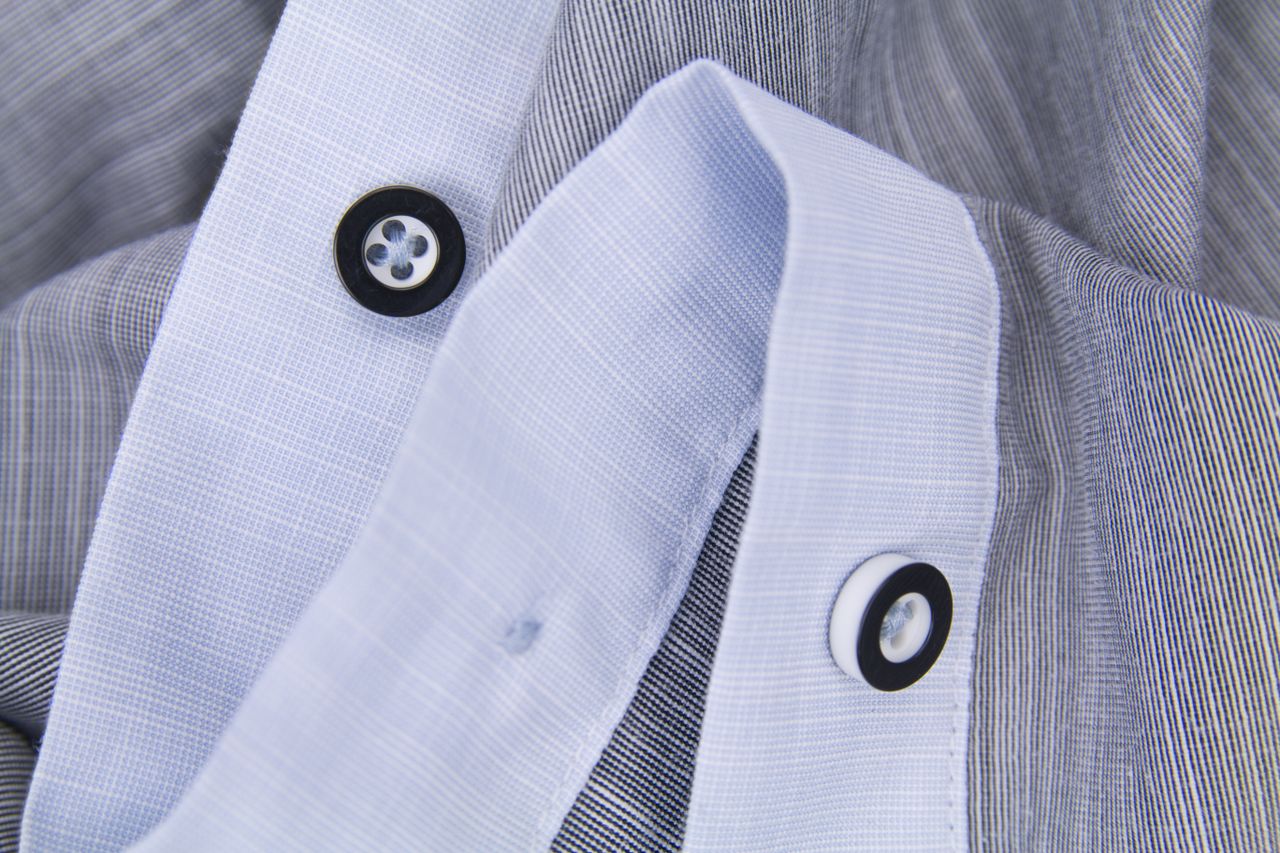 Detailed close-up of black and white buttons on a striped shirt showcasing fabric texture.